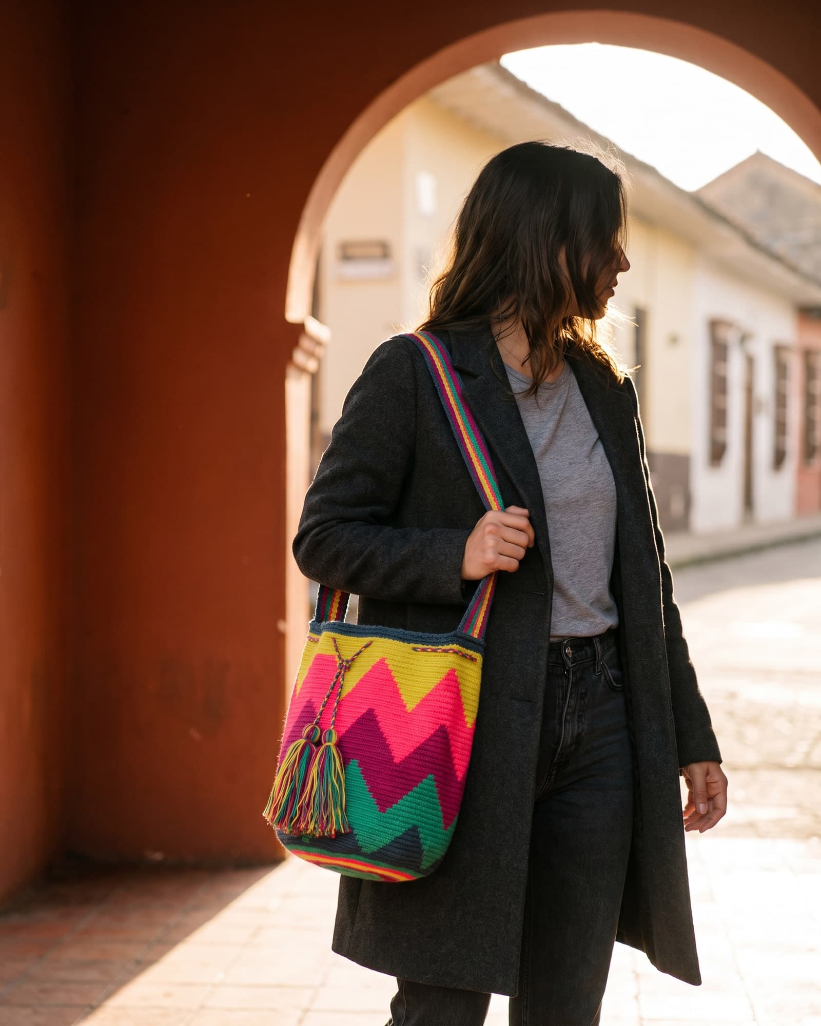 Frau mit abgewandtem Gesicht trägt die zitronengelb-neonpinke Mochila Zigzag über der Schulter.