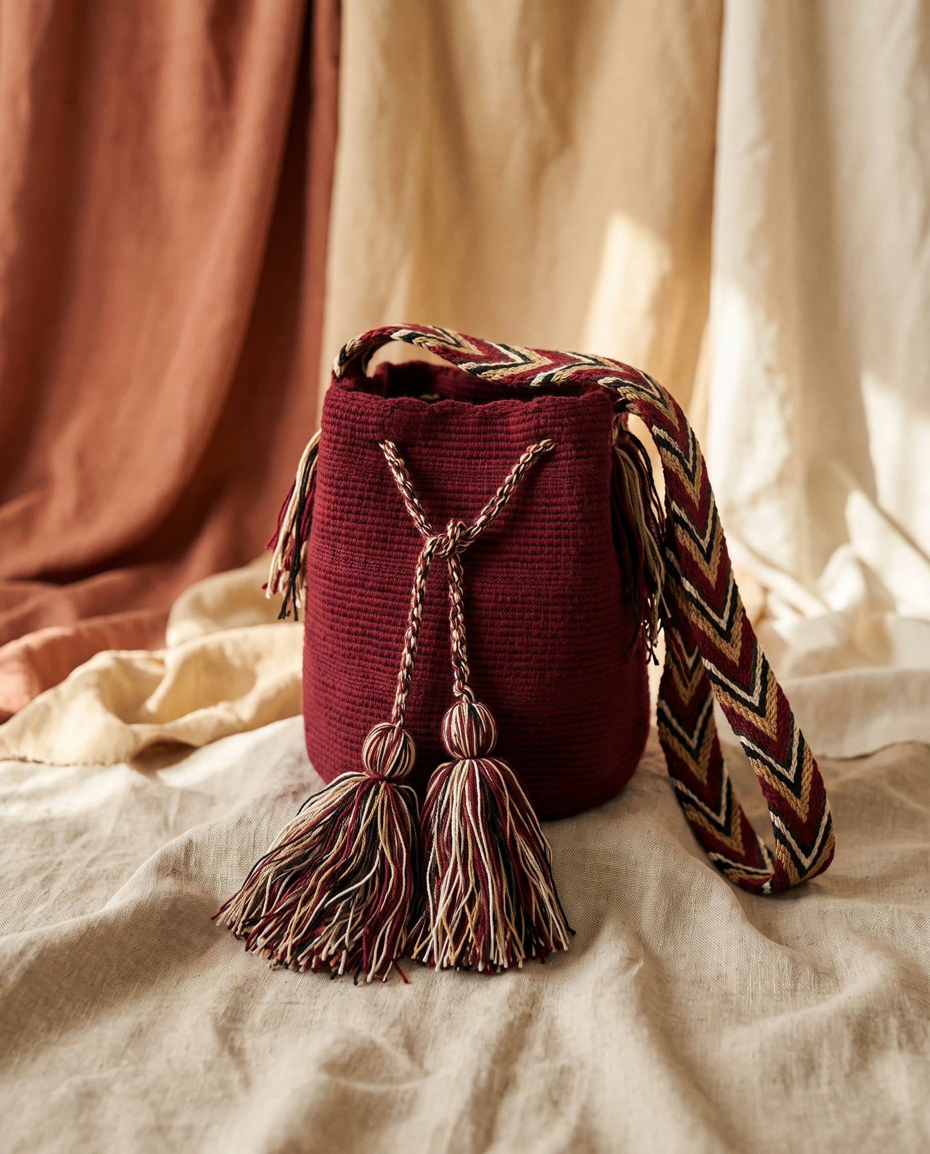 Handgewebte einfarbige Wayuu-Mochila in tiefem Weinrot auf Leinen