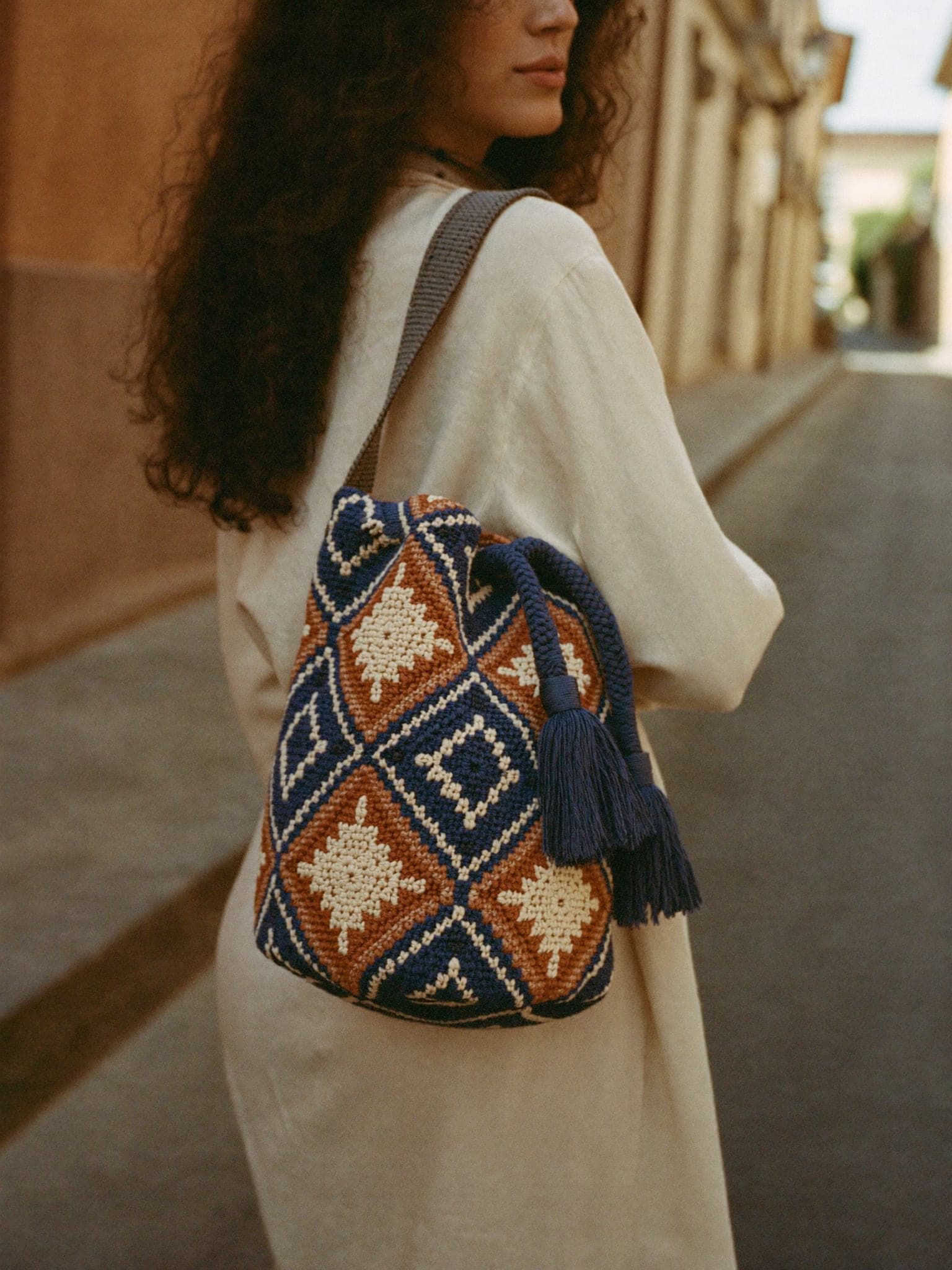 Woman in a linen dress carrying a handwoven Wayuu mochila over her shoulder